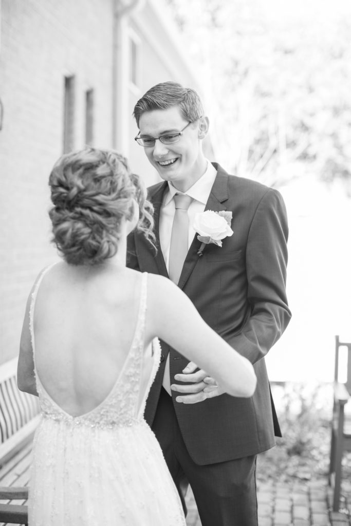 A groom smiles joyfully as he sees his bride for the first time.