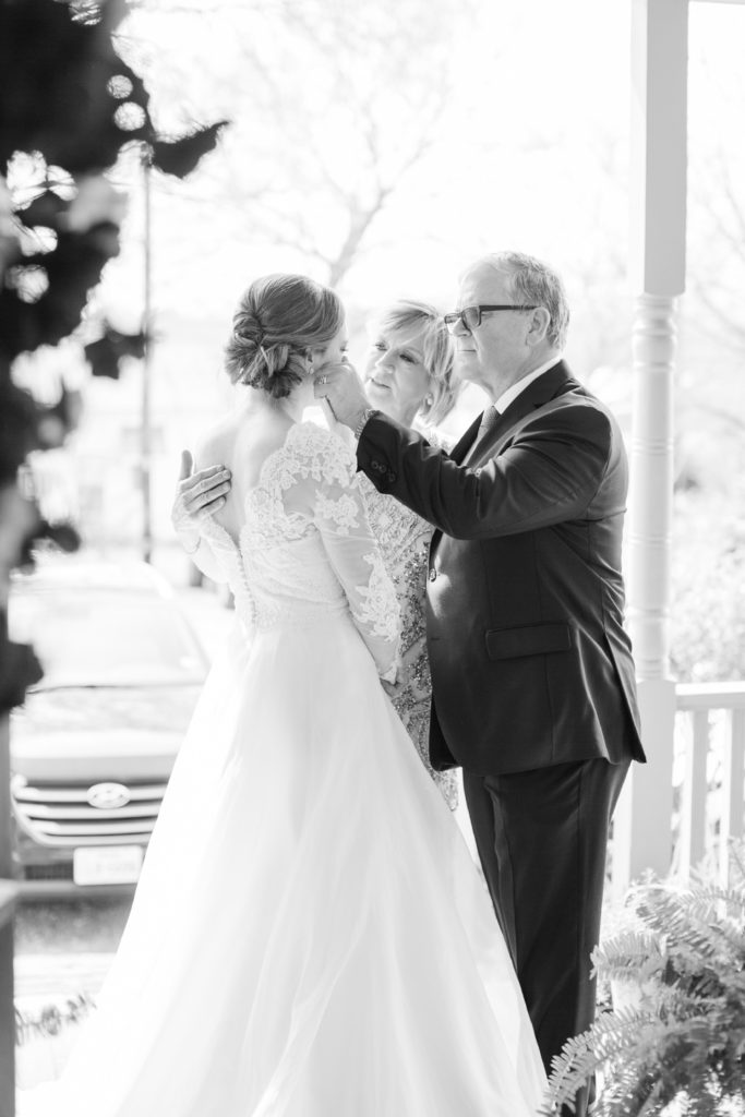 A mother and father wipe a tear from a brides eye on her wedding day.