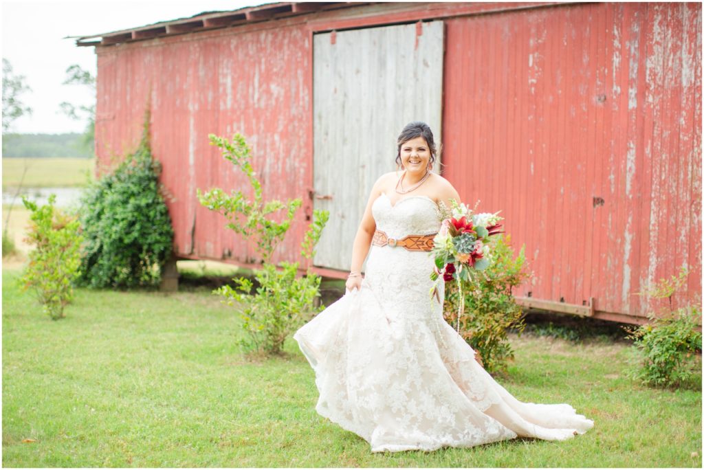 A bride laughs in front of an old red train car.