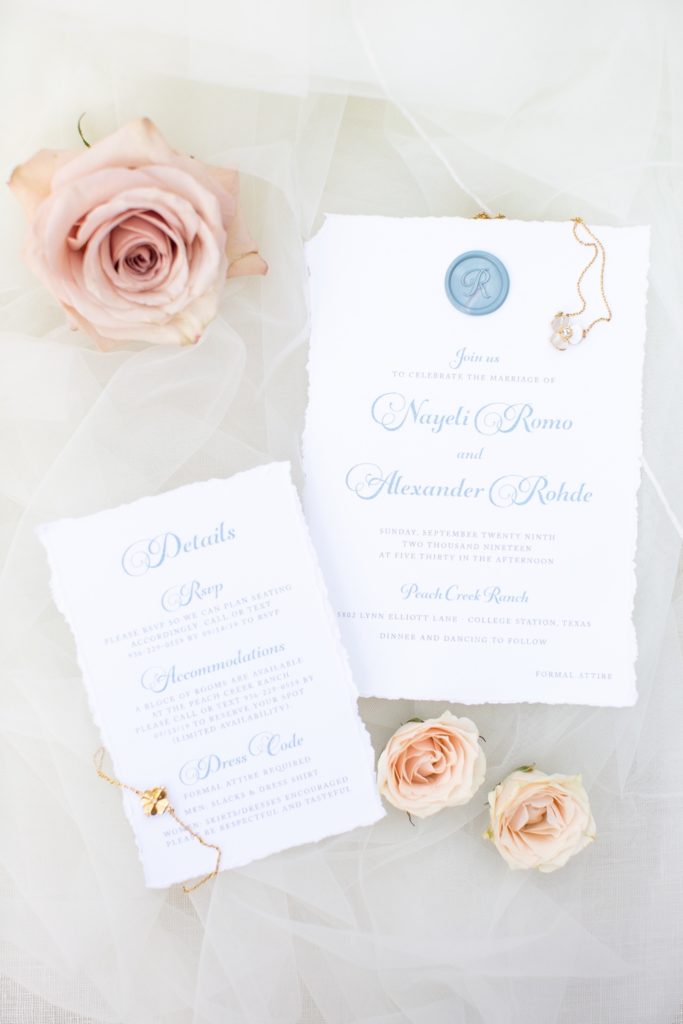 Classy wedding invitations styled with roses on a wedding gown.