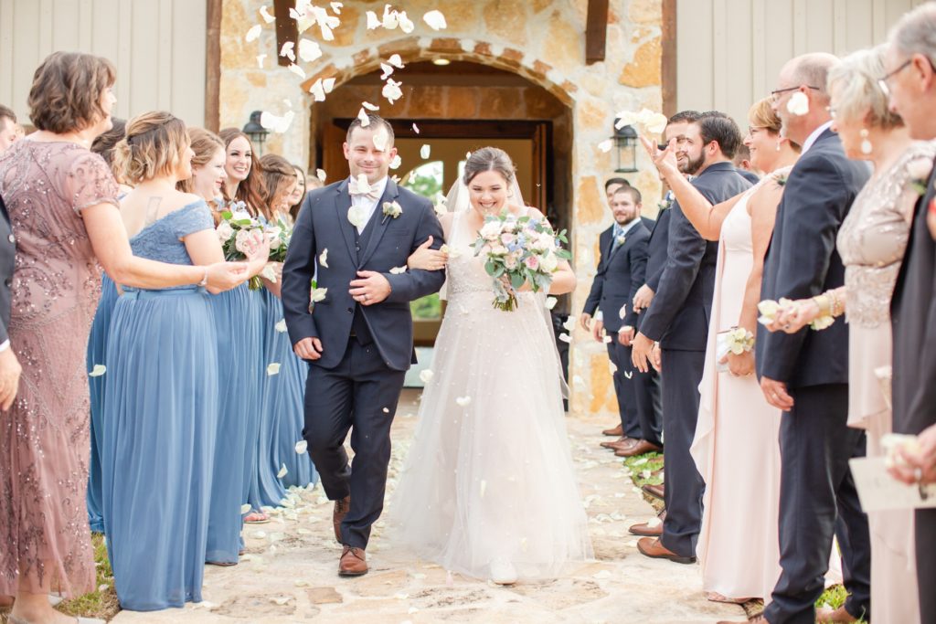 Guests throw wedding petals on the bride and groom as they exit their wedding ceremony.