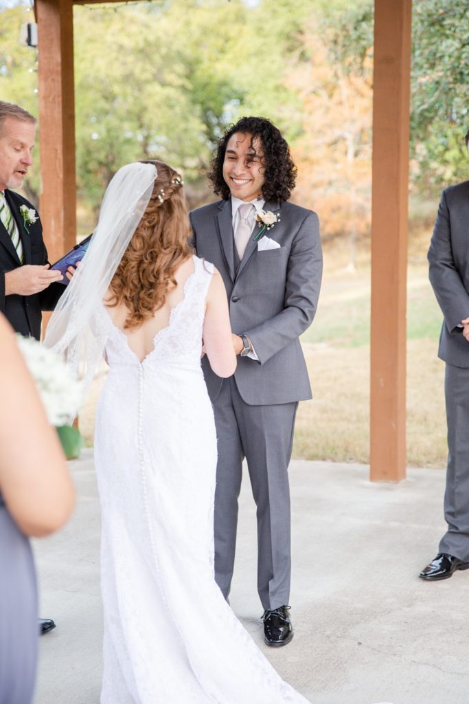 A groom smiles at his bride during their wedding ceremony.
