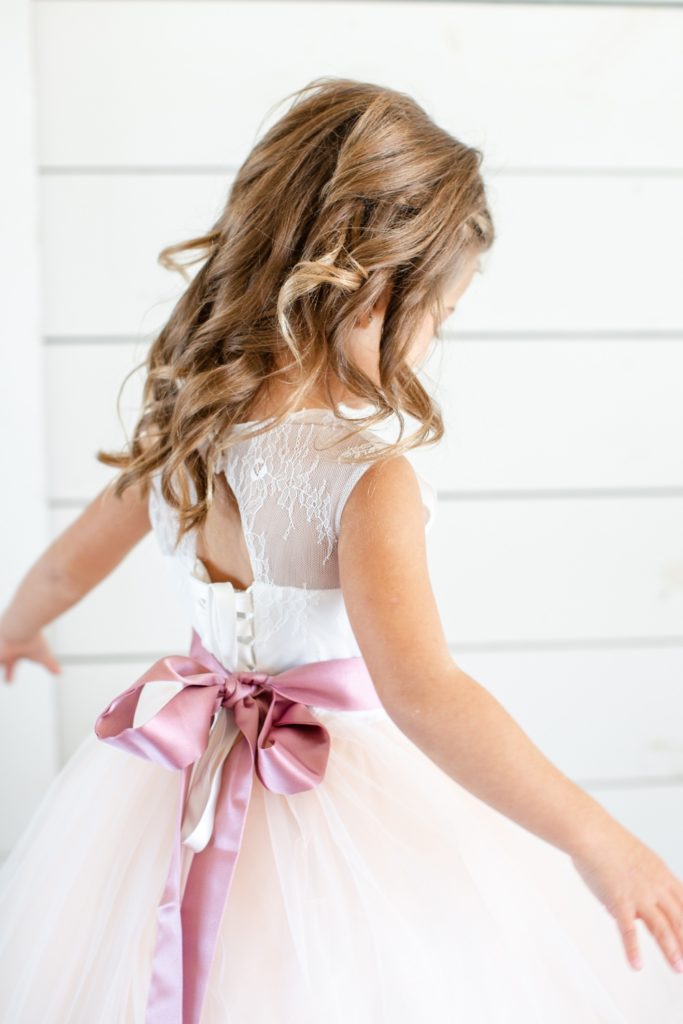 A flower girl twirls in her dress.