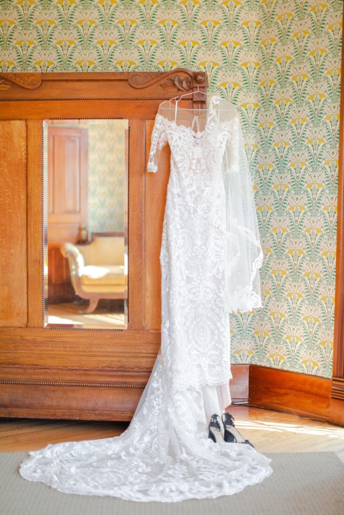 A wedding dress delicately hangs next to a chesnut wardrobe in a 1900s small town Texas house. 