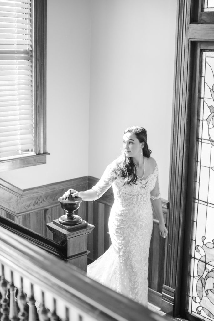 A bride makes her way down a winding staircase to meet her groom outside.