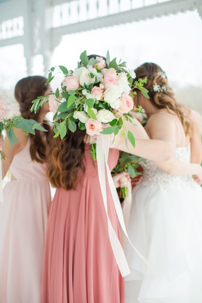 A bride hugs her bridesmaids on her wedding day.