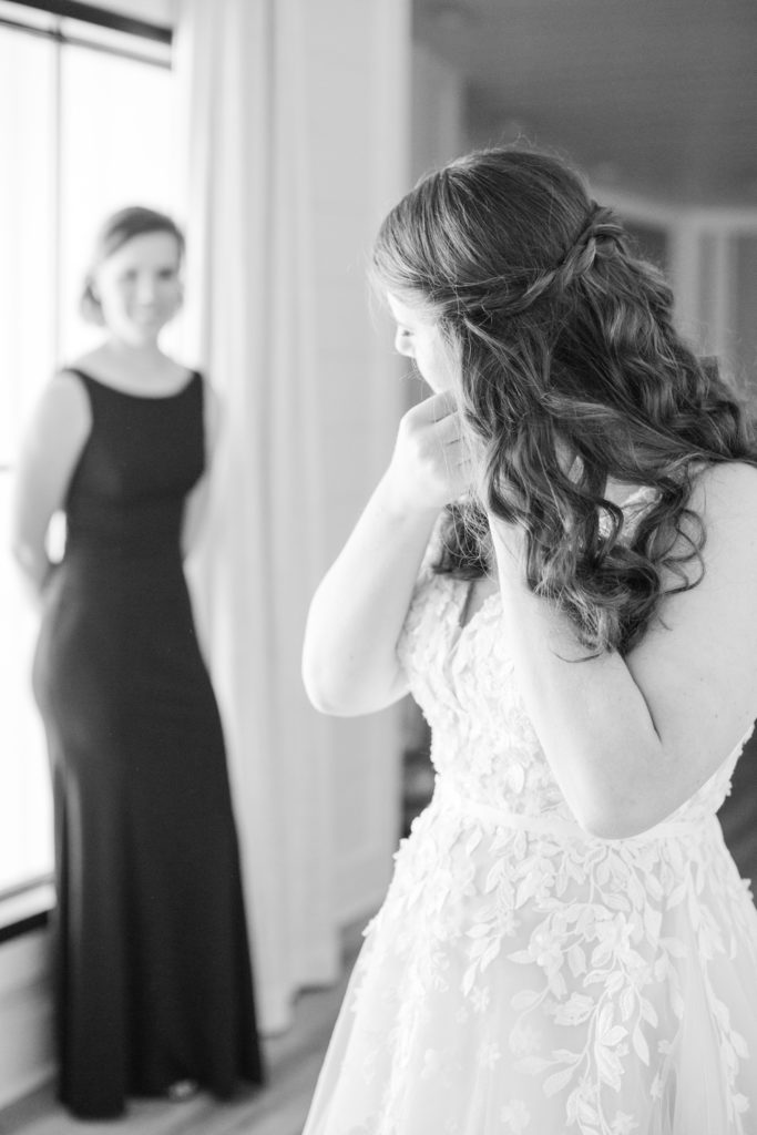 Big sister watches little sister get dressed on her wedding day.