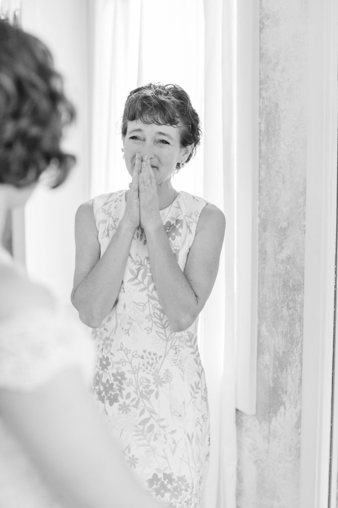 A mother cries as she sees her daughter in her wedding dress for the first time.